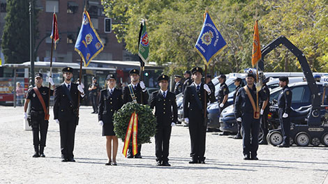Formación de policías con corona de flores y banderas homenajeando a los caídos