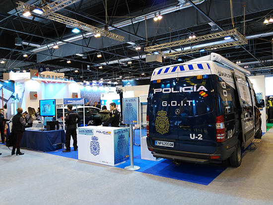 Stand de la Policía, furgón del Grupo Operativo de Intervenciones Técnicas, mostrador informativo y varias mesas con equipos policiales