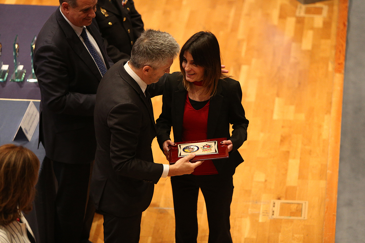 El Ministro del Interior entrega a una mujer una placa conmemorativa, en presencia del Director General de la Policía.
