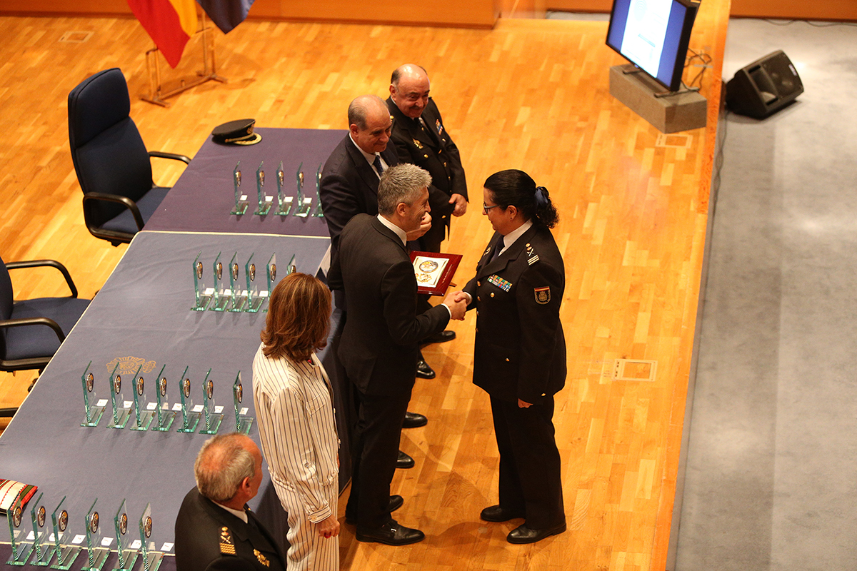 El Ministro del Interior entrega una placa conmemorativa a Dª Pilar Allué, Subdirectora General de Recursos Humanos, en presencia de autoridades. 