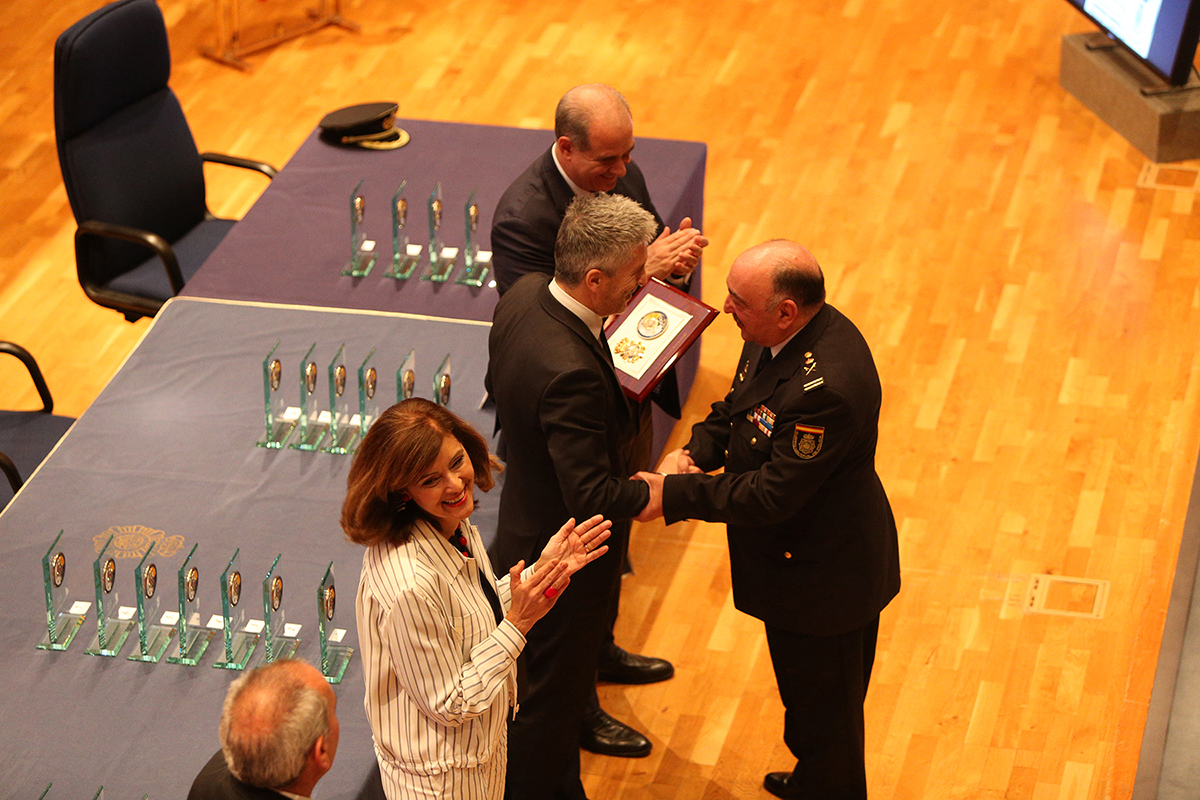 El Ministro del Interior entregando una placa conmemorativa al Comisario General de Policía Científica a la vez que se estrechan la mano. 