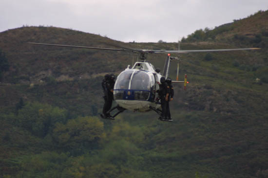 Helicóptero de Policía Nacional en vuelo de poca altura transportando a miembros de Unidades Especiales que se encuentran en el exterior del aparato.