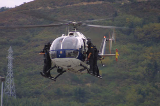 Helicóptero de Policía Nacional en vuelo de poca altura transportando a miembros de Unidades Especiales que se encuentran en el exterior del aparato.
