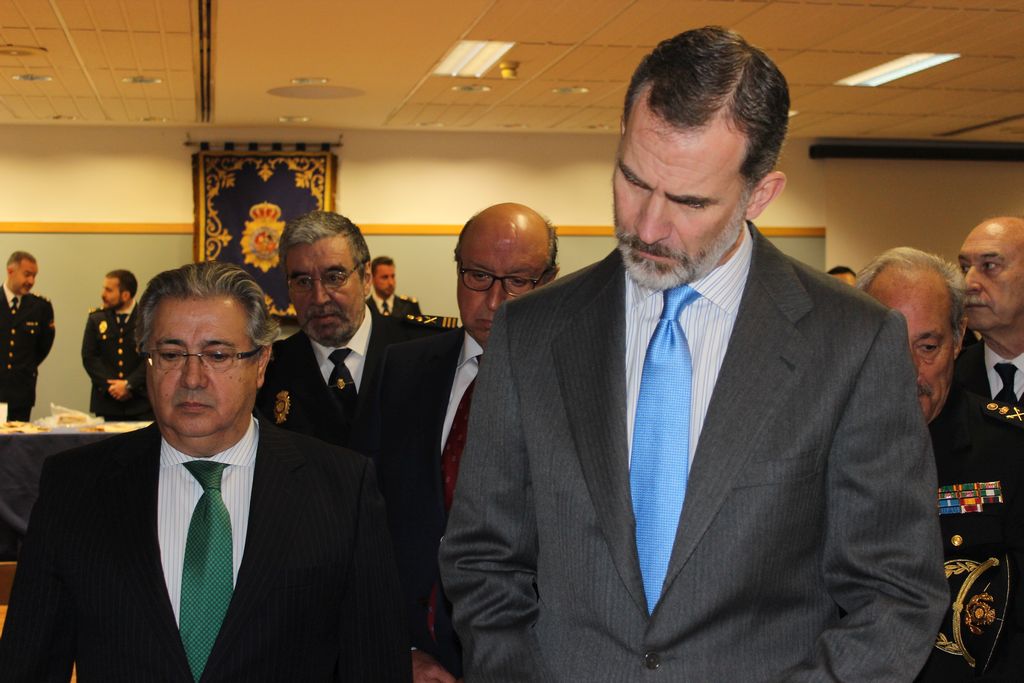 S. M. el Rey D. Felipe VI junto al Ministro del Interior y otras autoridades policiales, observando la exposición.