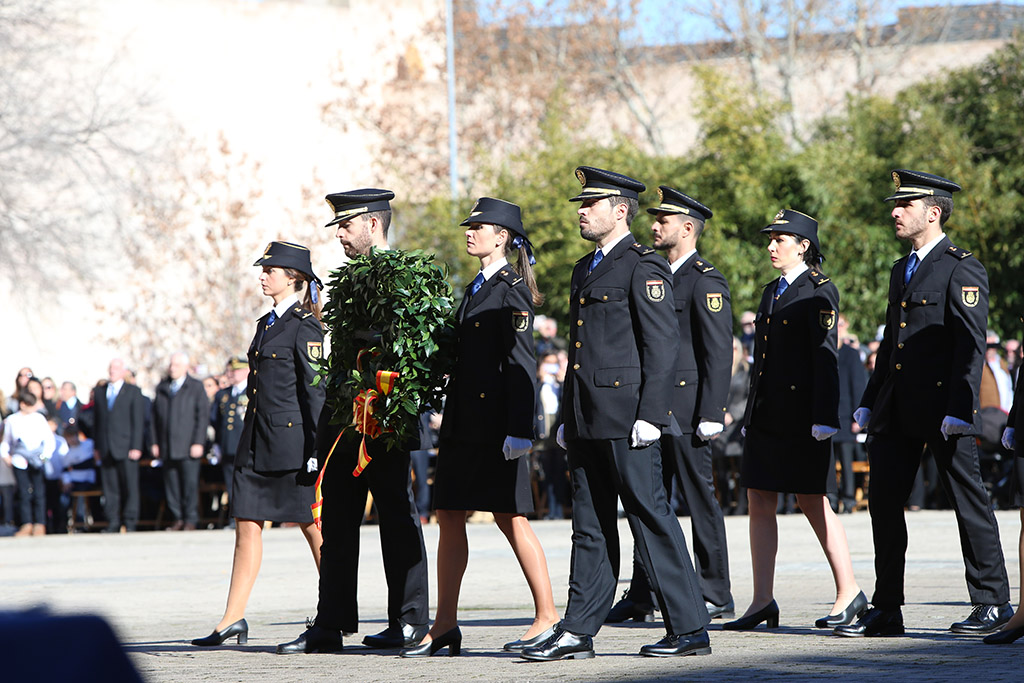 Hombre y mujer uniformados portando una Corona, junto a a otros cinco policías uniformados.