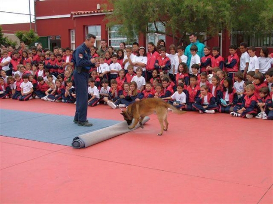 Exhibición a menores en un patio, un Policía Nacional de la Unidad de Guías Caninos con su respectivo perro, realizando un ejercicio de búsqueda.