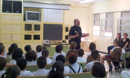 Un policía de la Unidad Central de Participación Ciudadana y Programas, dando una charla a alumnos menores y sus profesoras en un aula.