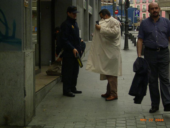 Un policía nacional realiza una identificación y un control de metales a un hombre en la vía pública.