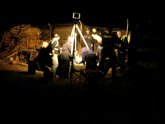 Policías Nacionales trabajando en la noche, alrededor de un pozo iluminados por lámpara.