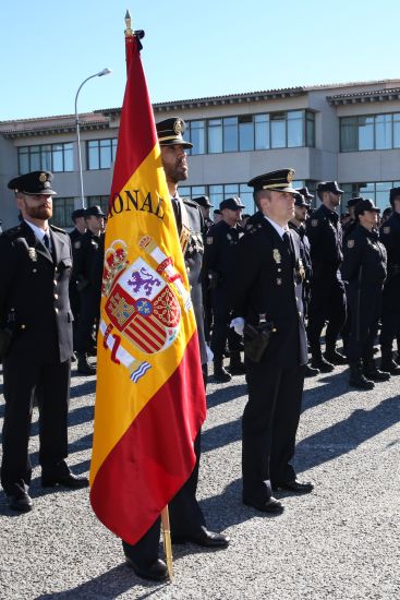 Grupo de Policías Nacionales en formación, portando el primero de ellos una bandera grande de España.