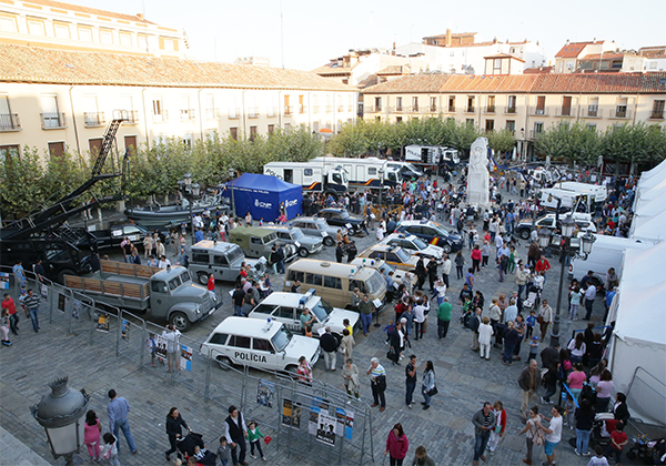 Fotografía tomada desde altura de la exposición de vehículos policiales. Se ven todos los vehículos y muchos visitantes.