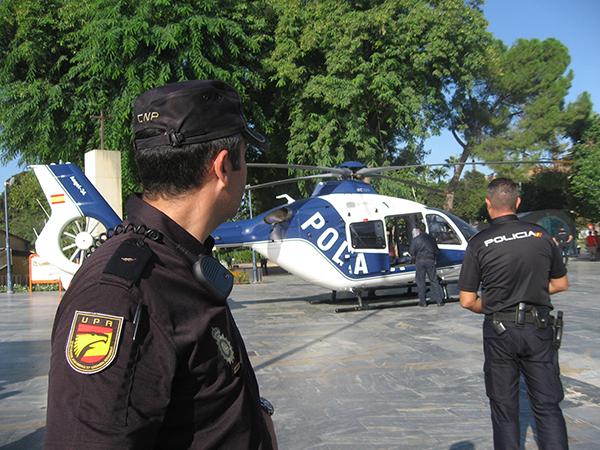 En primer plano, dos policías de la UPR mirando hacía el helicóptero de la Policía Nacional que se encuentra al fondo de la imagen en el suelo.
