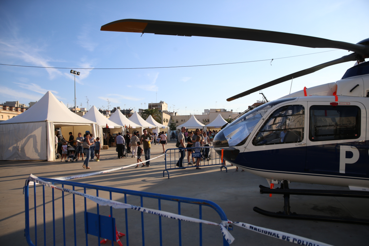 Primer plano de helicóptero en la exhibición de vehículos y de público visitando las carpas de la Policía Nacional.
