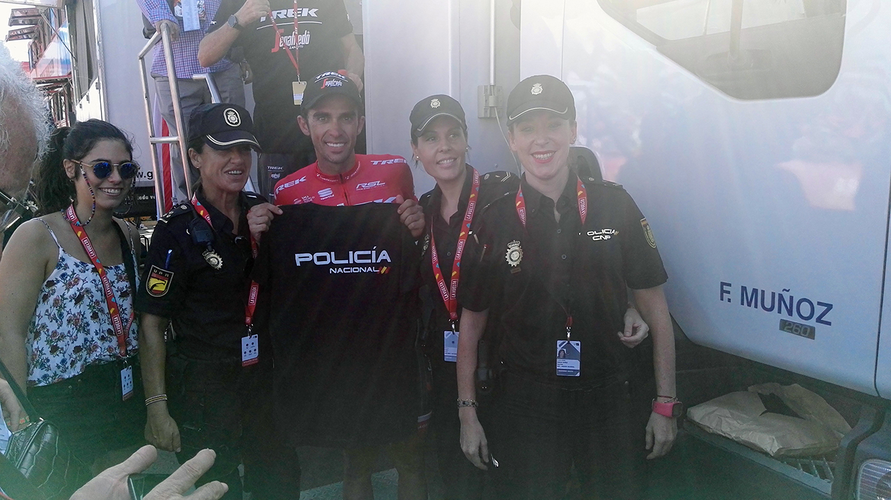 Alberto Contador mostrando la camiseta de la Policía Nacional junto a tres miembros de policía y una asistente a la vuelta