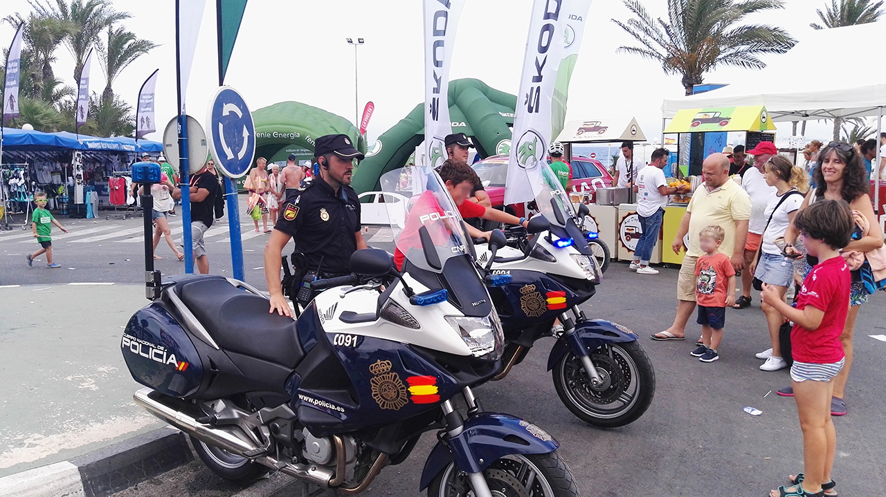 Niño montado en motocicleta policial junto con dos agentes de la policía nacional  y varias personas mirando al niño
