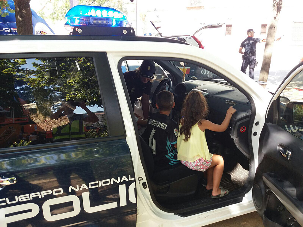 Dos niños con una agente dentro de un vehículo policial