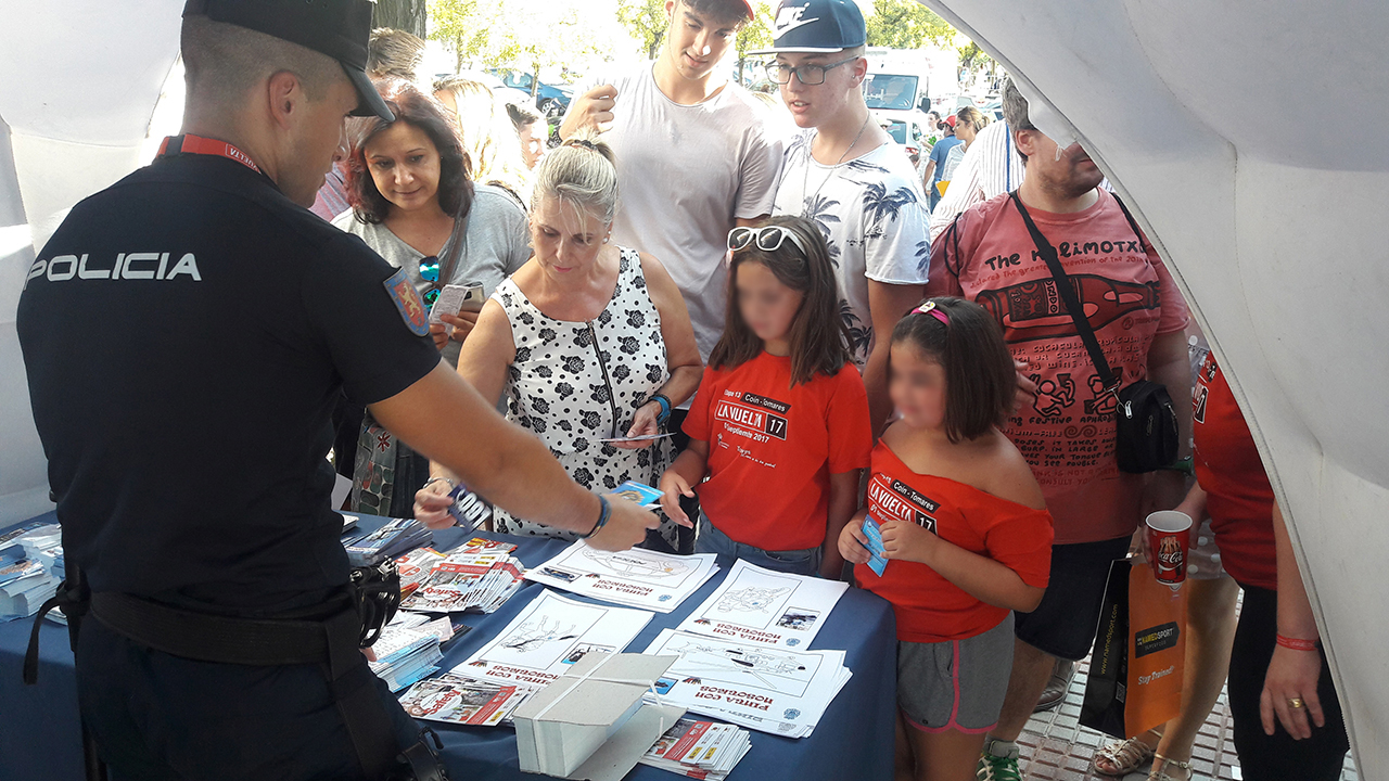 Niños y adultos recogiendo pegatinas, folletos, etc,  de la carpa informativa de la Policía Nacional