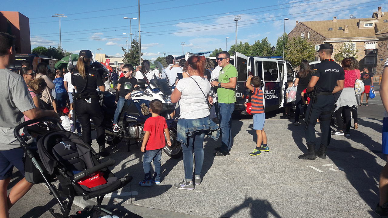 Una policía junto con niño subido en la motocicleta y numeroso público rodeando los vehículos policiales