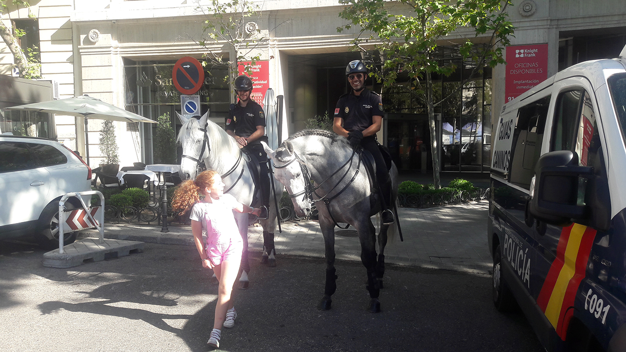 Niña delante de dos policías a caballo