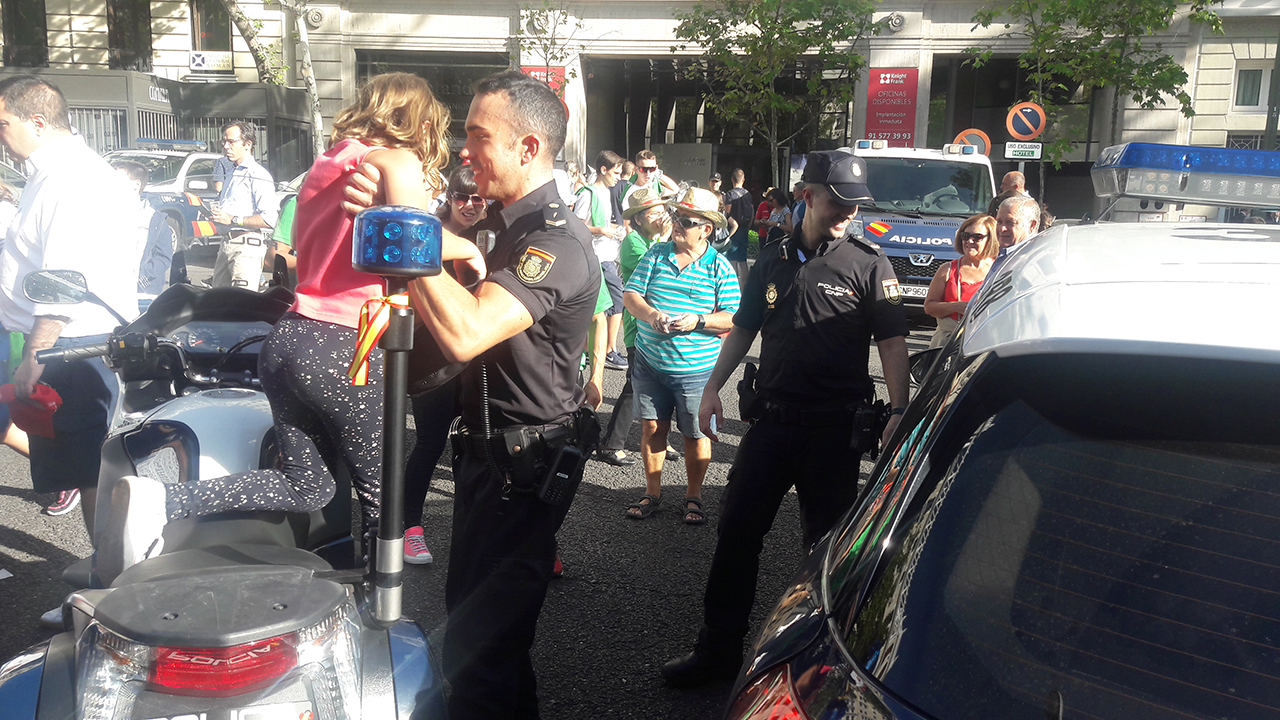 Agente de policía bajando a una niña de una motocicleta, junto a ellos otro agente 