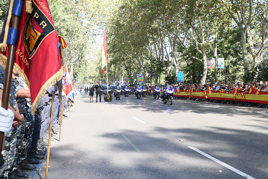Desfile de vehículos de la Policía Nacional, al paso siete motocicletas en formación de cuña, con las luces de emergencia encendidas.