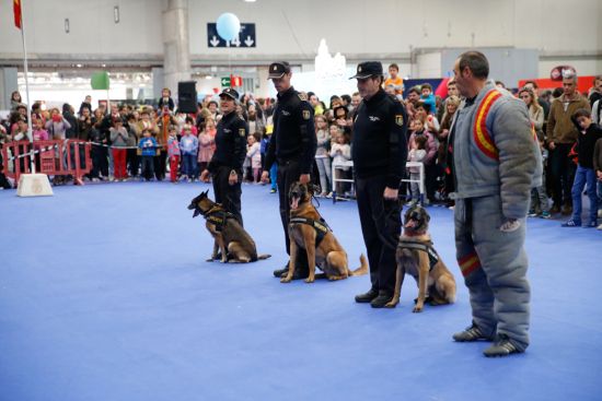 Miembros de la Unidad de Guías Caninos con sus perros y uno de ellos con el traje protector,  que usa para la exhibición.