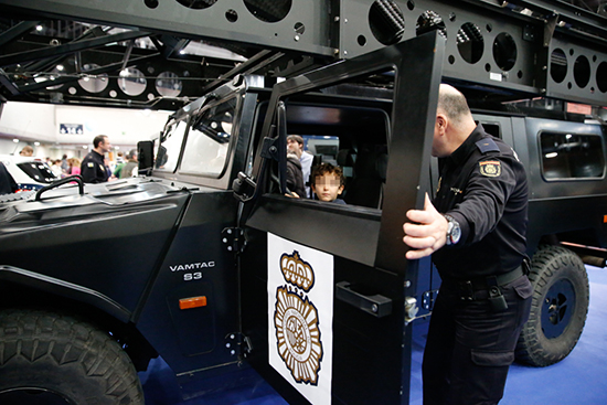 Niño dentro de vehículo de intervención del Grupo Especial de Operaciones y un agente de policía junto a él.