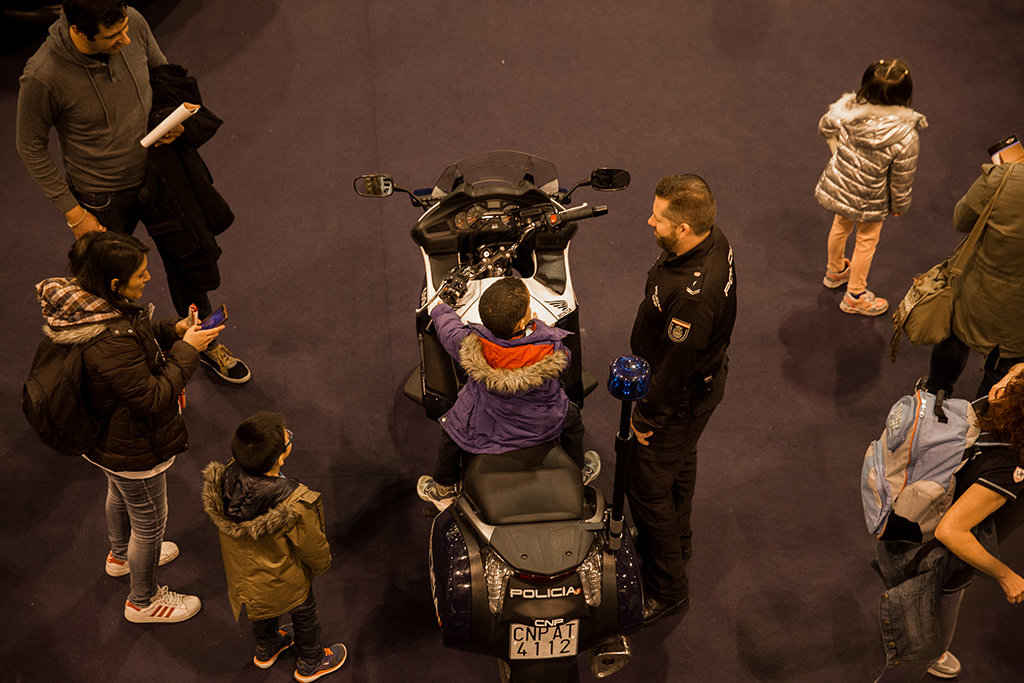 Niño subido en una motocicleta junto a él un agente controlando la seguridad del niño y familiares