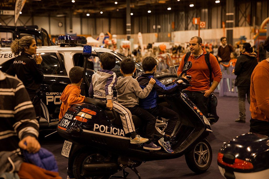 Tres niños subidos a una motocicleta supervisados por una agente de policía.