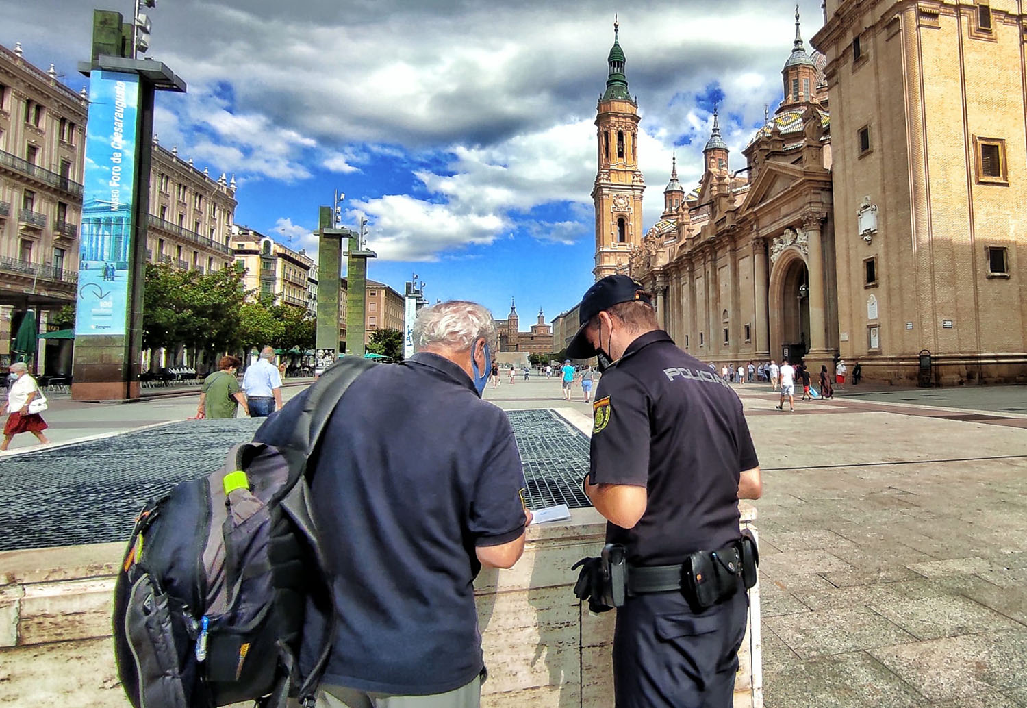 Un peregrino hablando con un Policía en la Plaza del Pilar