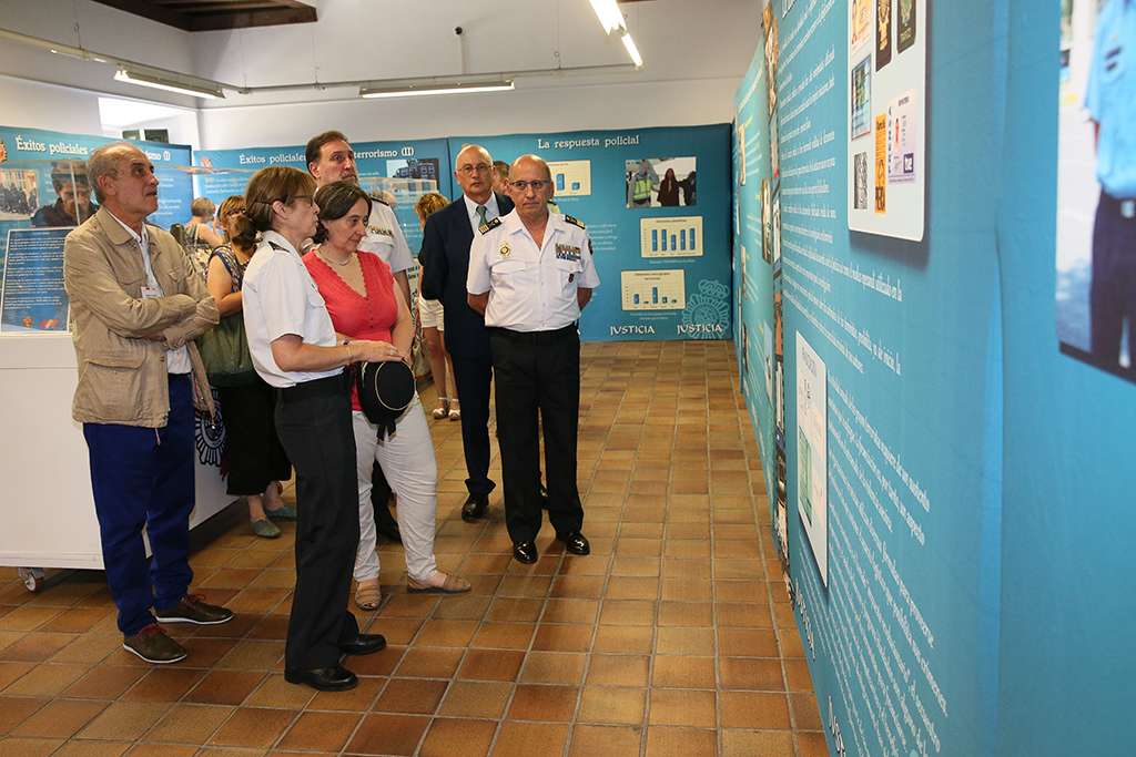 Autoridades y responsables policiales frente a un panel con fotografías e información relacionadas con la temática de la exposición.