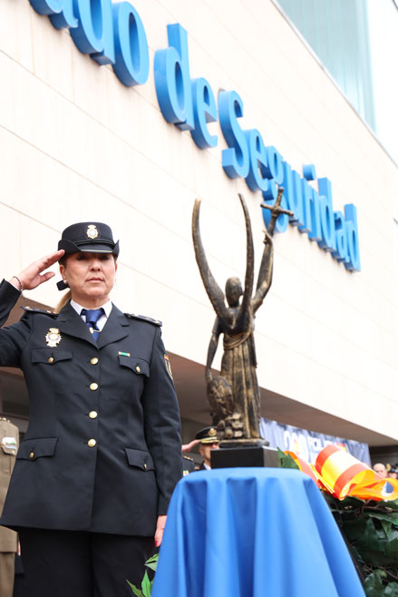 Agente femenina de la Policía Nacional haciendo el saludo reglamentario junto a la imagen del Ángel Custodio.