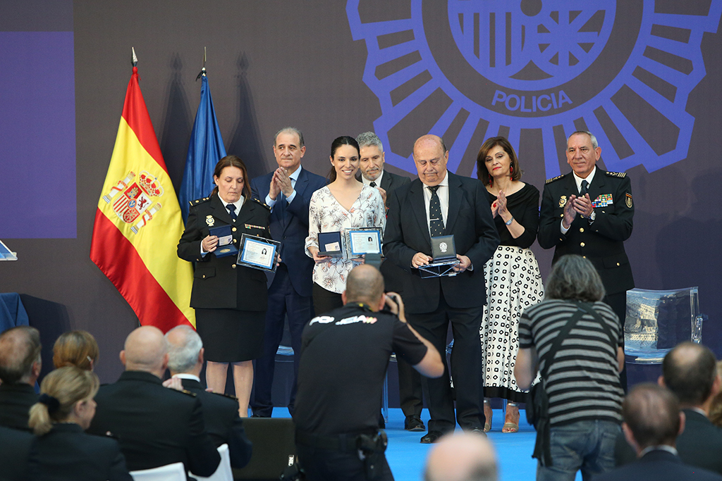 Dos mujeres, una de ellas uniformada, y un hombre, reciben los aplausos de diversas autoridades al recibir los premios de la gala 40 aniversario.