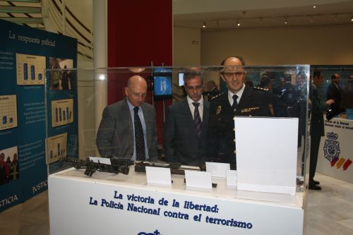 El presidente del T.S.J. de Castilla-La Mancha, junto al UCOP de Albacete observando varias ametralladoras en una vitrina de la exposición.