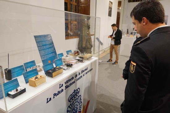 Un Policía Nacional observa una vitrina que contiene diverso material electrónico para la fabricación de bombas.