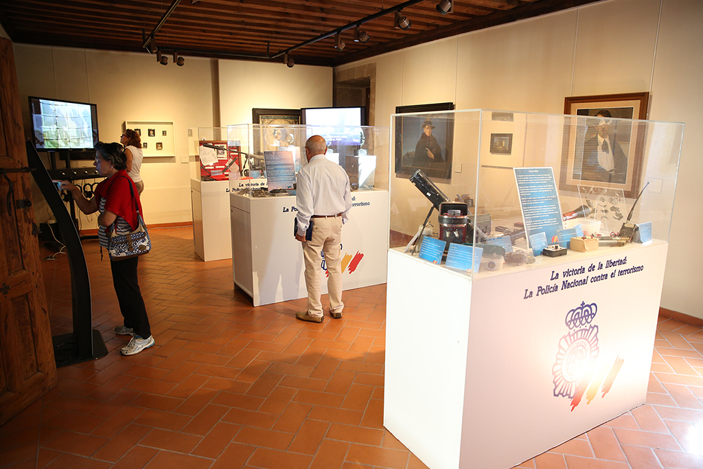 Varios visitantes observando distintos elementos de la exposición e interactuando con los paneles táctiles de información.