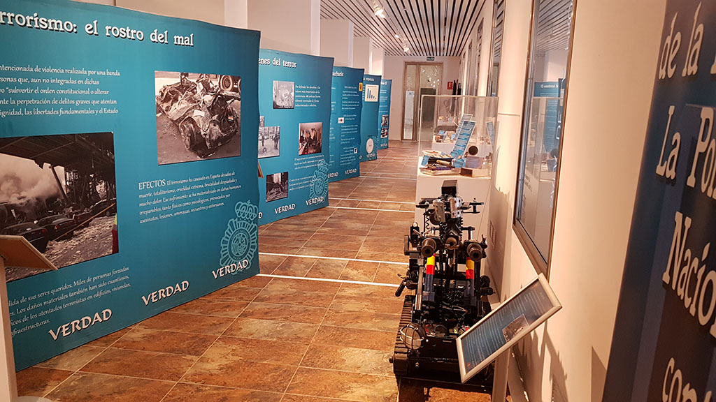 pasillo con varios paneles de información y fotografías de la exposición y un robot de TEDAX.