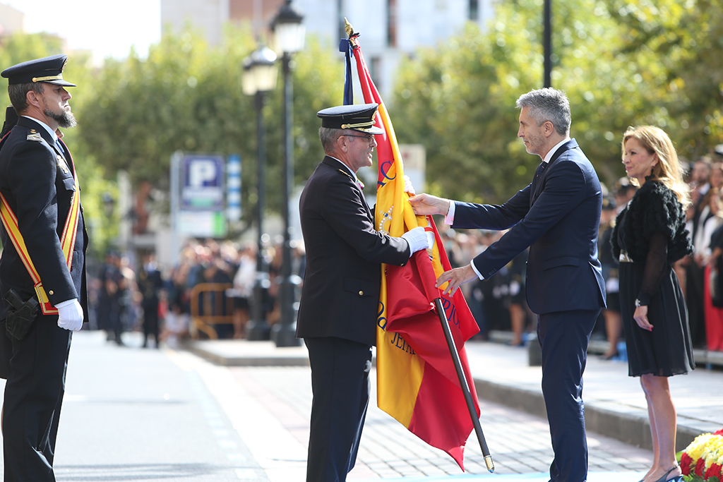 Hombre uniformado hace entrega de la bandera nacional al Ministro del Interior D. Fernando GRANDE-MARLASKA.