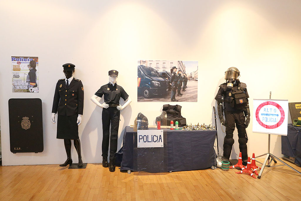 Maniquíes con uniformes de la Unidad de Intervención Policial y material para control de vehículos. En la pared dos carteles y escudo policial.