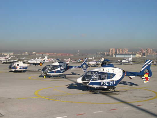 Foto panorámica de la pista con tres helicópteros de la Policía Nacional y varios aviones estacionados.
