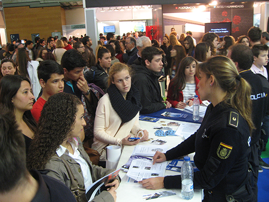 Mujer policía informando a jóvenes, chicos y chicas, sobre ingreso en la Policía Nacional.