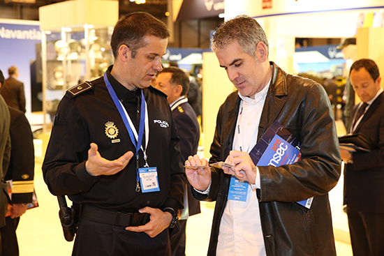 Un agente de policía con un asistente a la feria analizando un DNI electrónico.