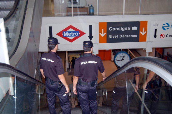 Dos Policías Nacionales de uniforme bajando las escaleras mecánicas para bajar al Metro de Madrid.
