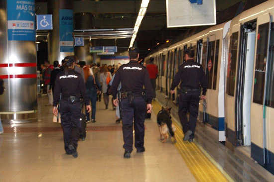 Tres Policías Nacionales patrullan un andén de metro con un perro de la Unidad de Guías Caninos.