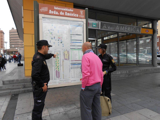 Un policía da indicaciones a un ciudadano frente a un plano del intercambiador de Avenida de América en Madrid, en compañía de una policía.