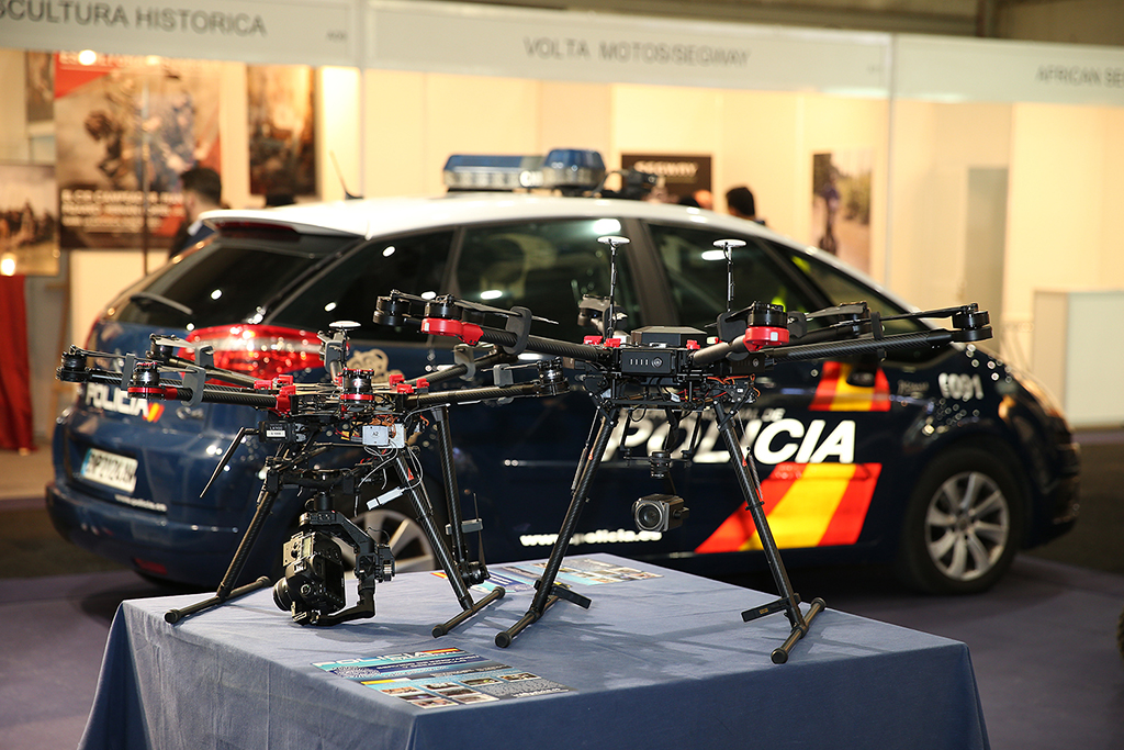 En primer plano dos drones de vigilancia sobre una mesa. Al fondo,  vehículo policial, Citroen C4 Picasso, rotulado.