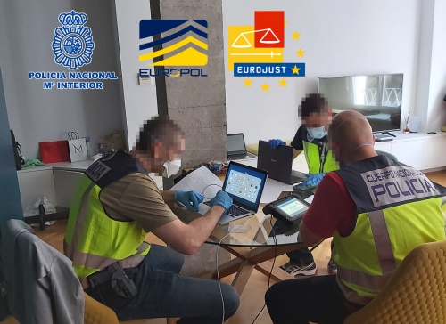 Tres agentes de policía  en una mesa, con tres dispositivos, dentro de la vivienda registrada