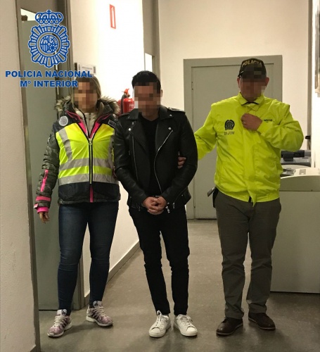 Dos agentes de policía custodiando a un arrestado que está esposado